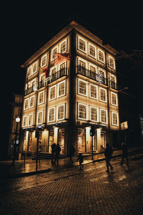 Free A brightly lit street view showcasing an elegant building in Porto, Portugal during nighttime. Stock Photo