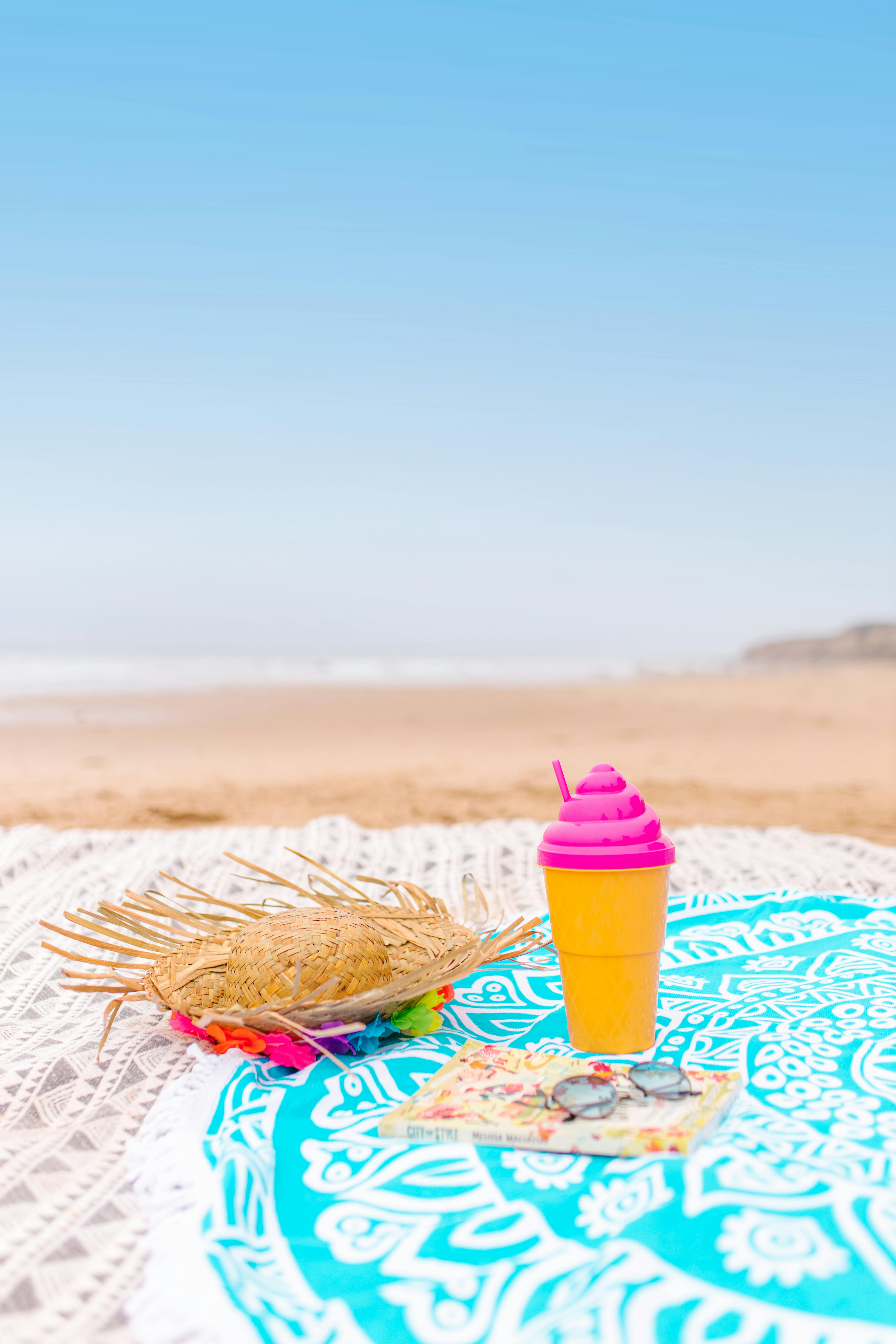 充满活力的夏日场景，海滩上有遮阳帽、饮料和书籍