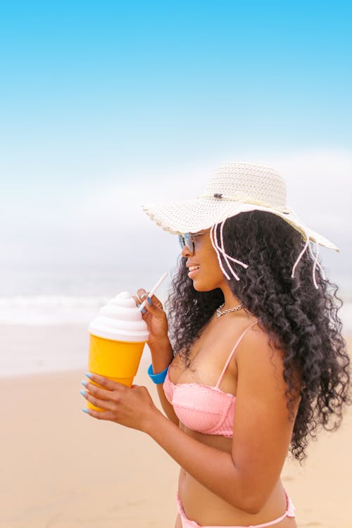 Free Woman in White Sun Hat and White Bikini Top Holding Yellow Cup Stock Photo