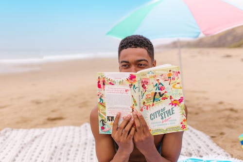 Free Man Holding a Book at the Beach Stock Photo