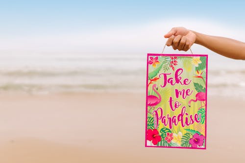 Free Person Holding a Paper Bag with Text and Floral Print Stock Photo