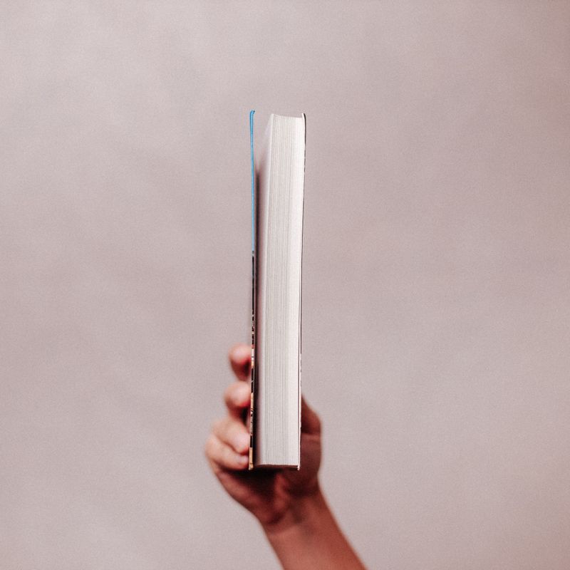 A hand holding a closed book — photo by Luis Quintero on Pexels