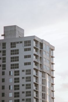 A modern glass-panel high-rise building photographed from a low angle against a clear sky.