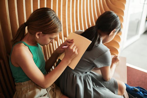Free Girls Sitting on the Bench while Writing Stock Photo