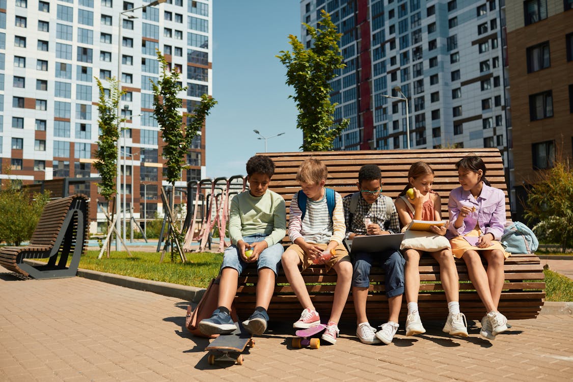 Free Children Sitting on a Brown Wooden Bench in the Park Stock Photo