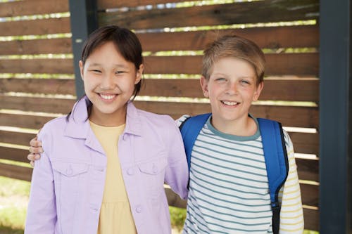 Free Smiling Boy in Blue and White Striped Shirt Beside Smiling Woman in Yellow Blazer Stock Photo
