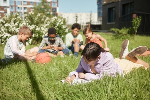 Free Children Sitting on Green Grass Field Stock Photo