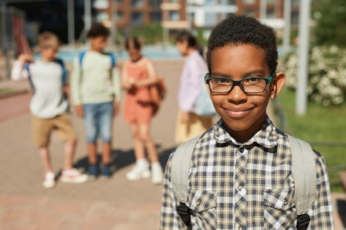 Photo of a Schoolboy in Eyeglasses with a Group of Friends Standing in the Background 