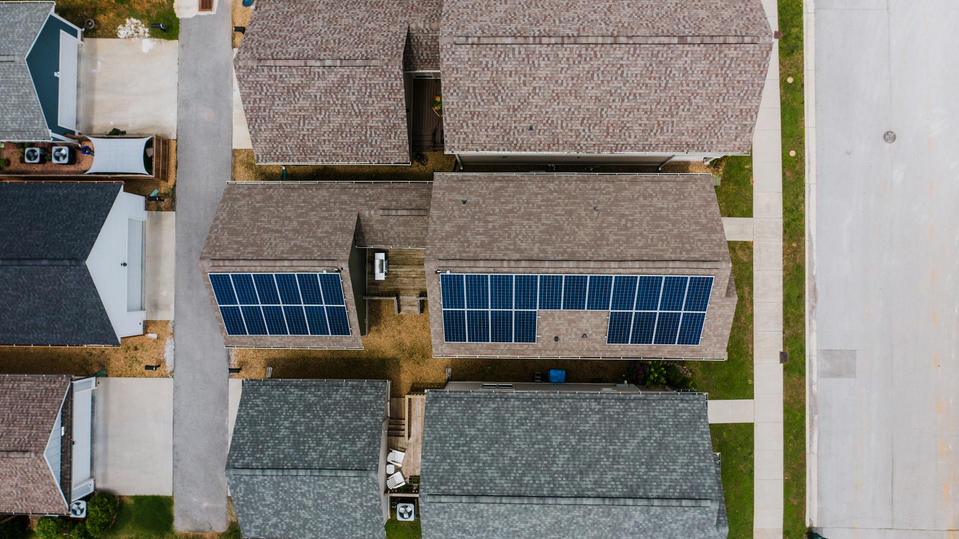 Top-down view of suburban houses featuring solar panels on roofs, showcasing renewable energy use.