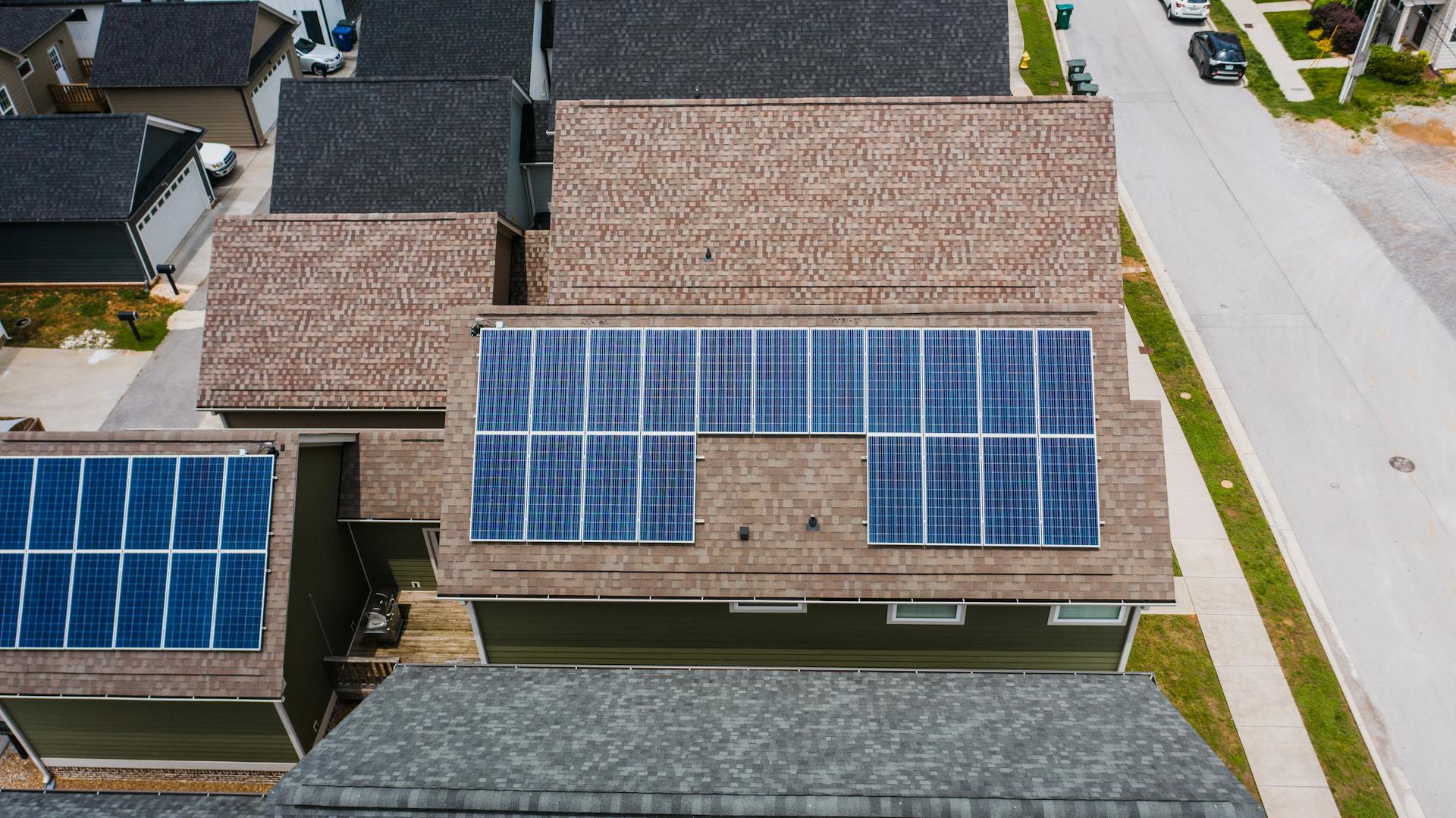 Drone shot of solar panels on residential roofs promoting eco-friendly energy solutions.