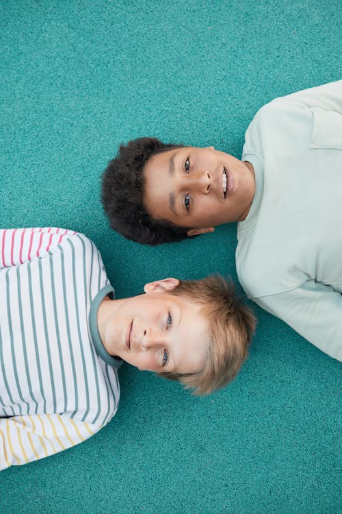 Free Boys Lying on a Blue Ground while Looking at the Camera Stock Photo