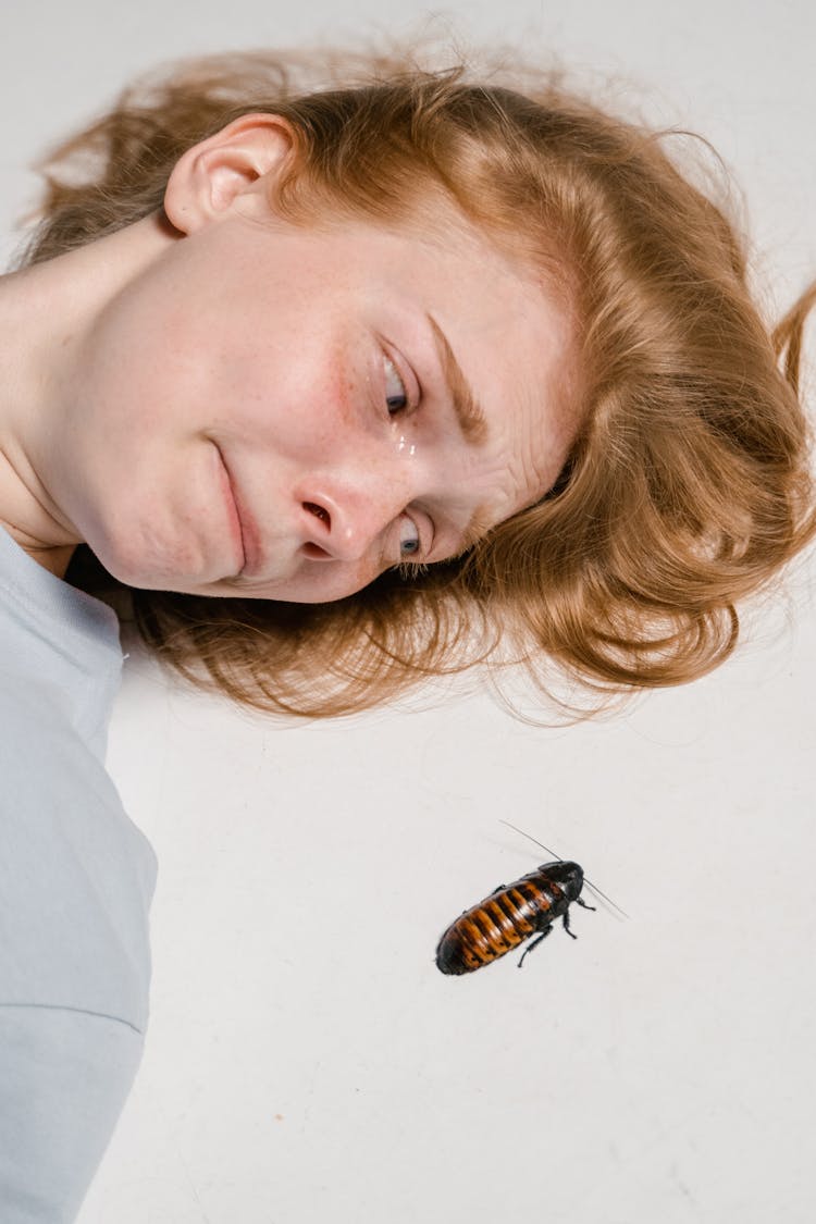 Close-Up Photo Of A Fearful Woman Lying Down While Overcoming Her Fear Of Cockroaches