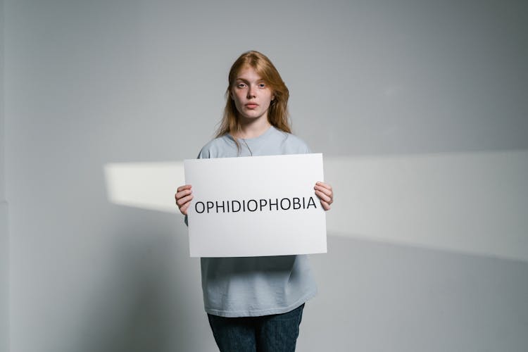 A Woman Holding A Sign Of Ophidiophobia