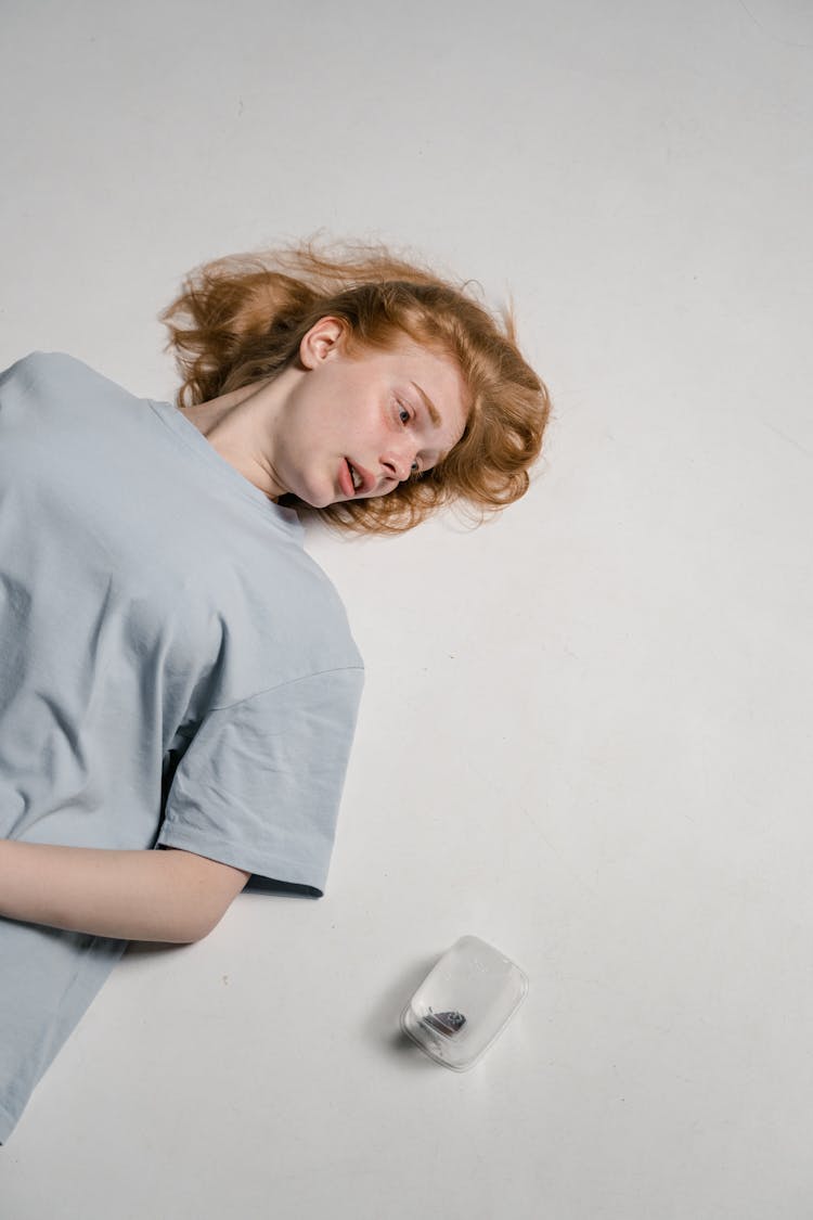 A Fearful Woman Lying Down While Looking At A Madagascar Hissing Cockroach In A Plastic