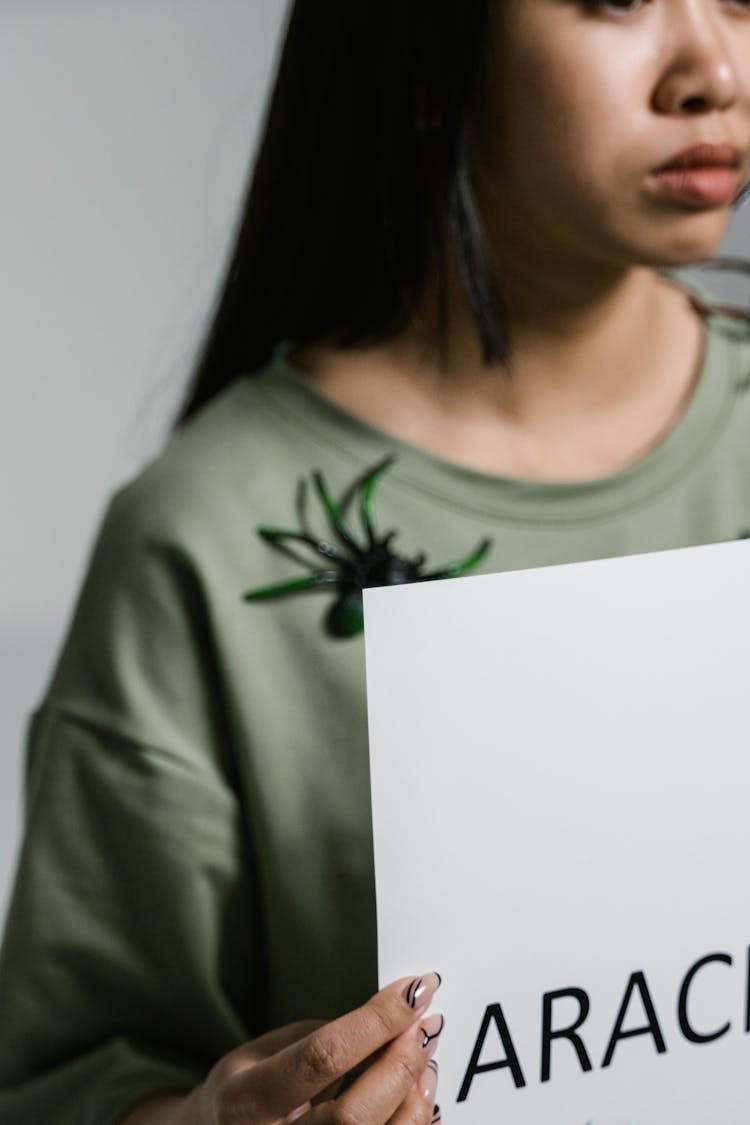 A Woman Holding A Sign Of Arachnophobia