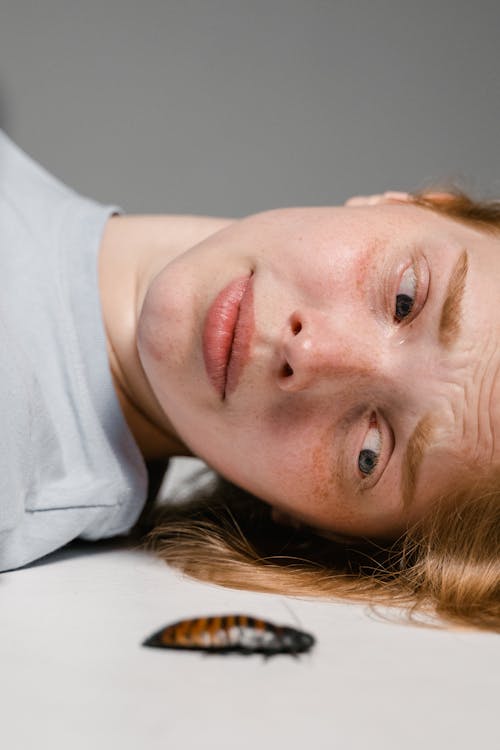 Close-Up Photo of a Fearful Woman Lying Down while Overcoming Her Fear of Cockroaches