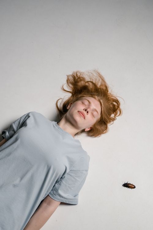 Free Woman lying down with a cockroach nearby, symbolizing facing fears. Stock Photo