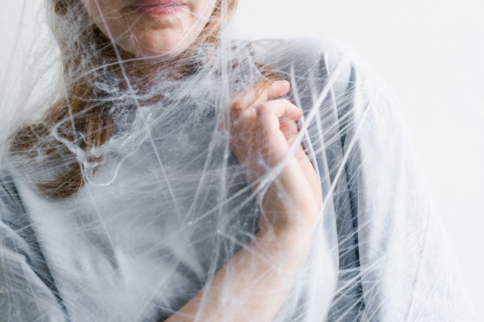 Close-up of a woman tangled in a spider web, symbolizing feelings of entrapment and anxiety.