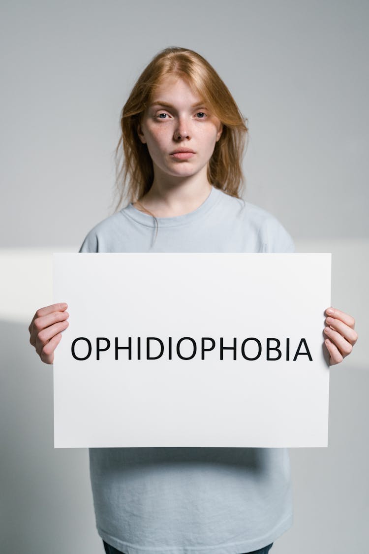 A Woman Holding A Sign Of Ophidiophobia