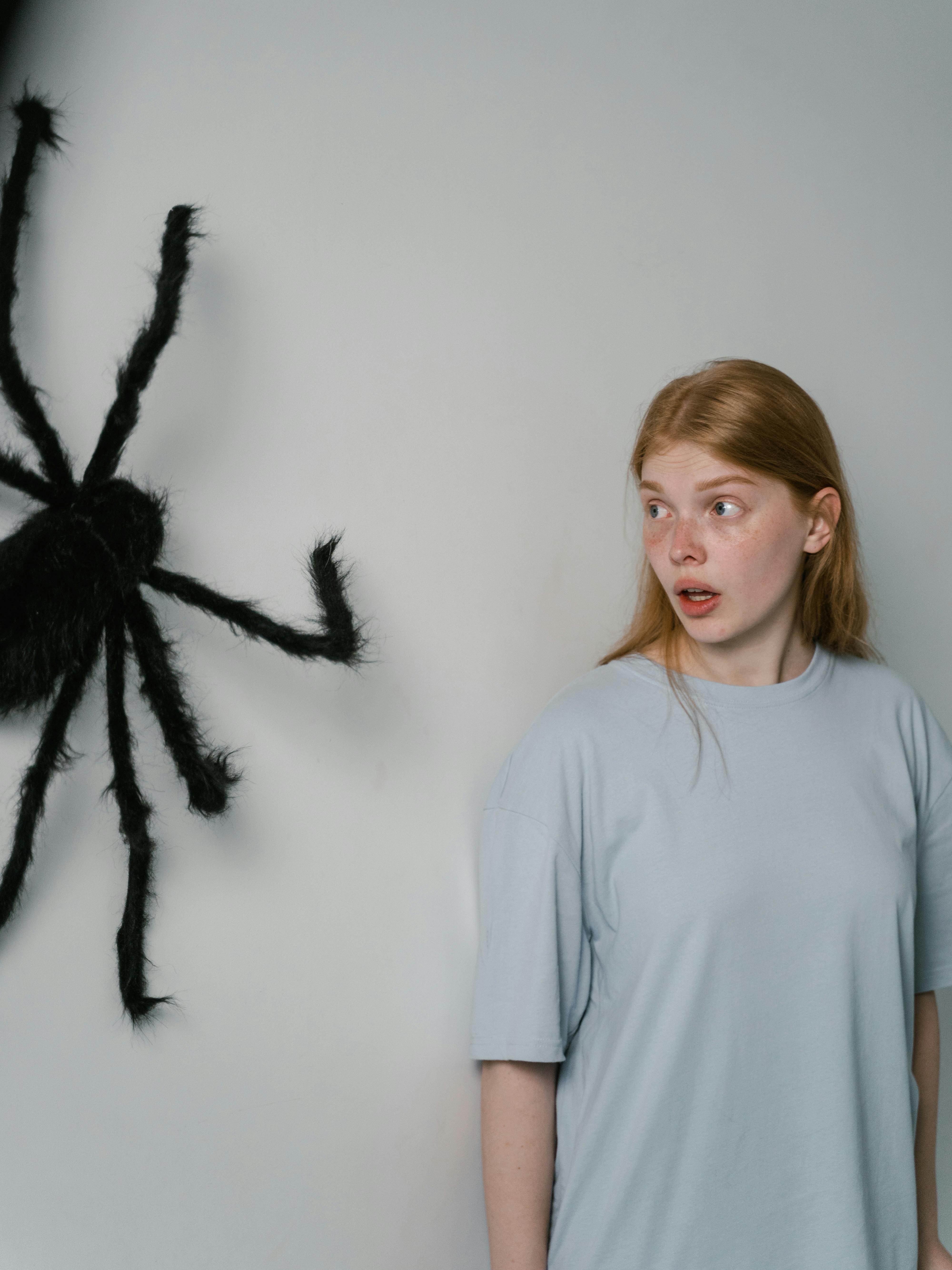 a woman afraid of big spider hanging on a wall