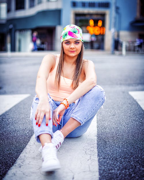 A Woman in Orange Tank Top Sitting on the Road