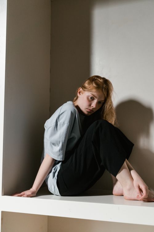 Free A woman sits in a confined corner, illustrating themes of anxiety and solitude. Stock Photo