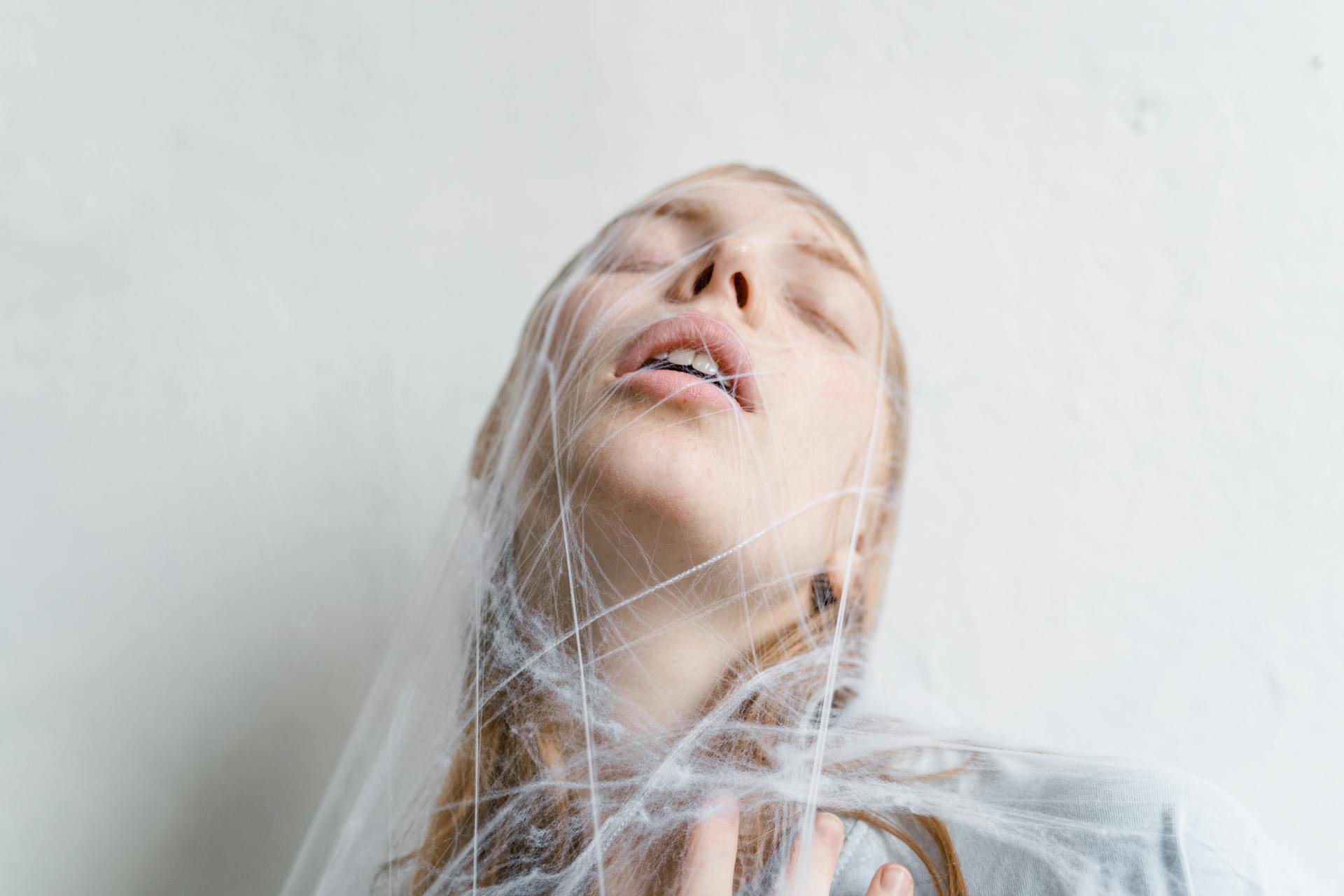 Close-Up Photo of a Helpless Woman Trapped in a Spider Web