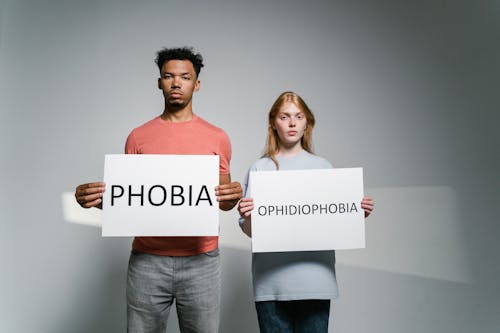 Free Man and Woman Holding Signs of Different Forms of Phobia Stock Photo