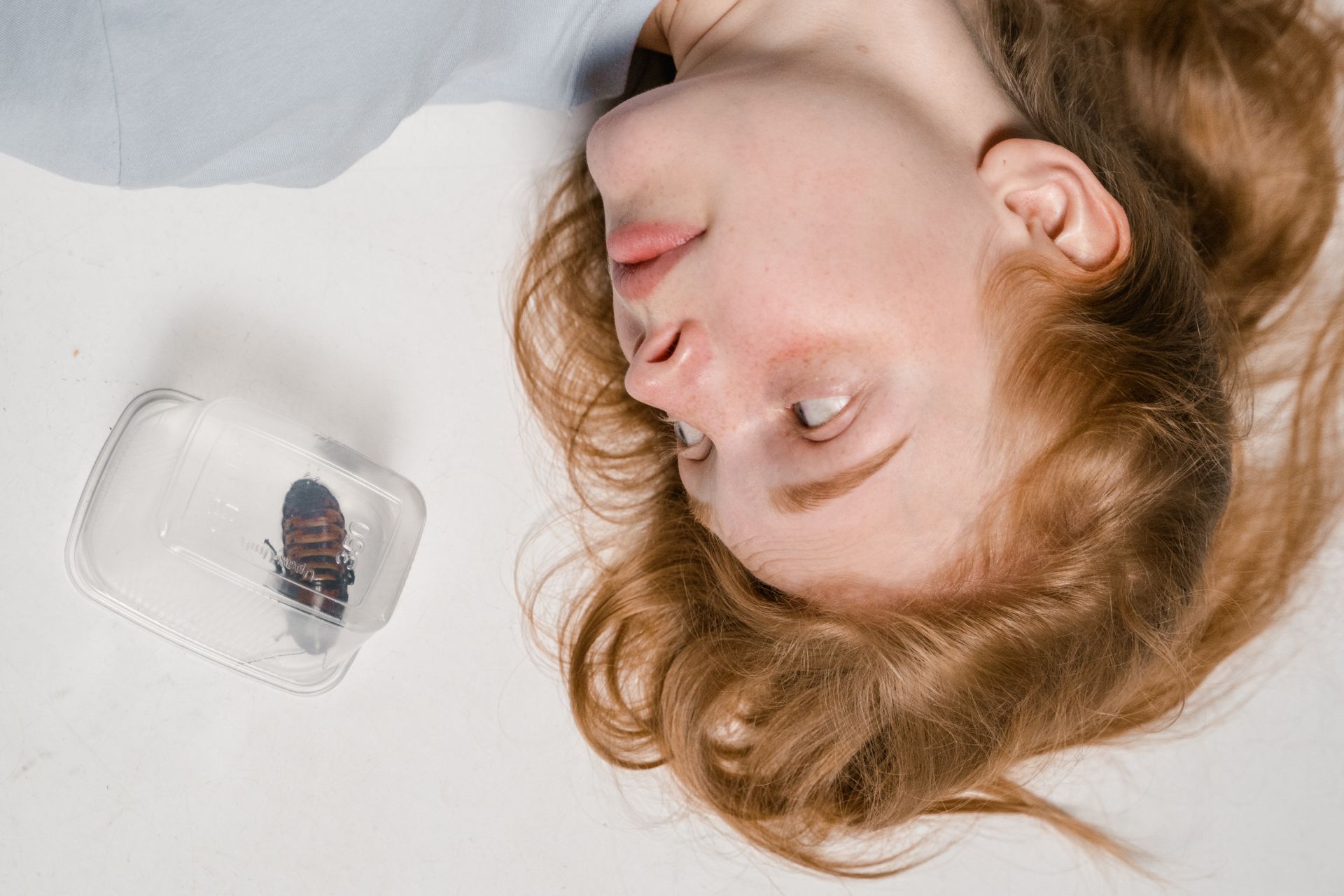 Close-Up Photo of a Fearful Woman Having Katsaridaphobia while Looking at the Madagascar Hissing Cockroach