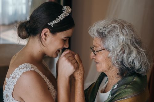 Free A bride and elderly woman share a tender embrace on a wedding day, symbolizing love across generations. Stock Photo