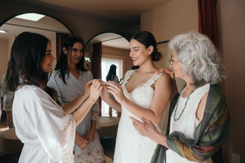 Free Bride shares a joyful moment with bridesmaids and elder woman, capturing wedding day happiness. Stock Photo