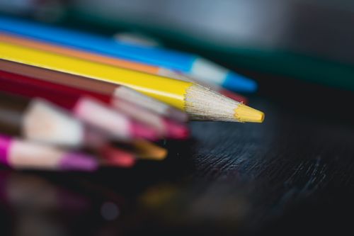 Free Macro shot of vibrant colored pencils with selective focus on yellow tip, placed on a dark surface. Stock Photo