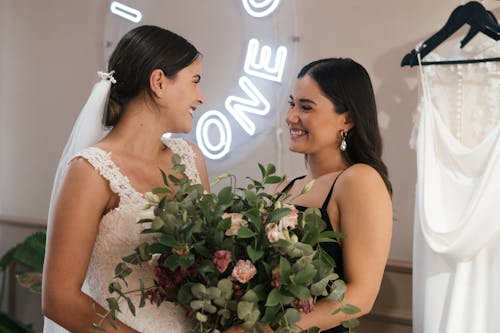 Woman in White Wedding Dress Smiling Beside Woman in Black Tank Top