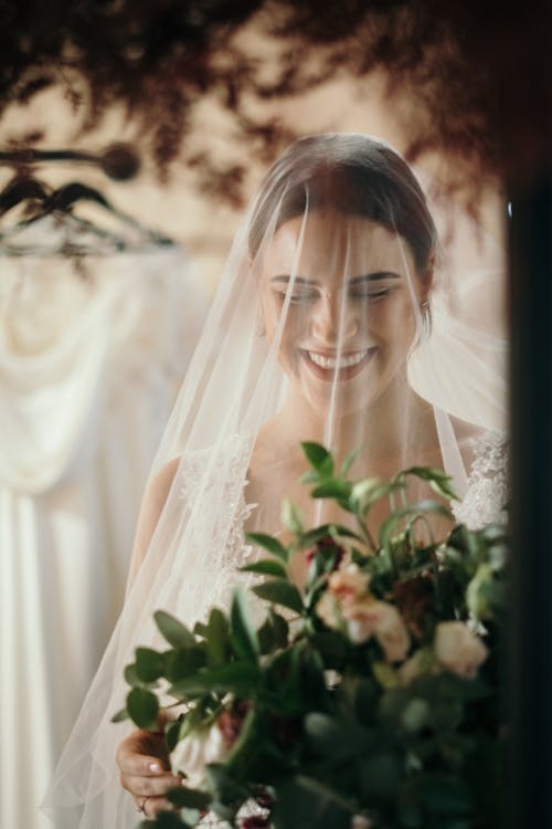 A Woman in White Wedding Dress Smiling while Wearing a Veil