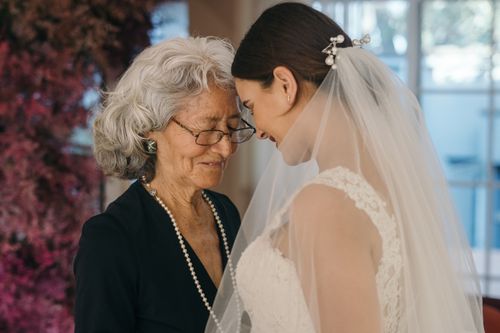 Free A bride shares an emotional connection with an elderly woman, eyes closed in a heartfelt moment. Stock Photo