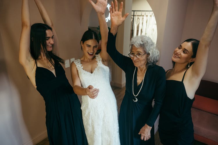 The Bride And Her Entourage With Their Hands Up