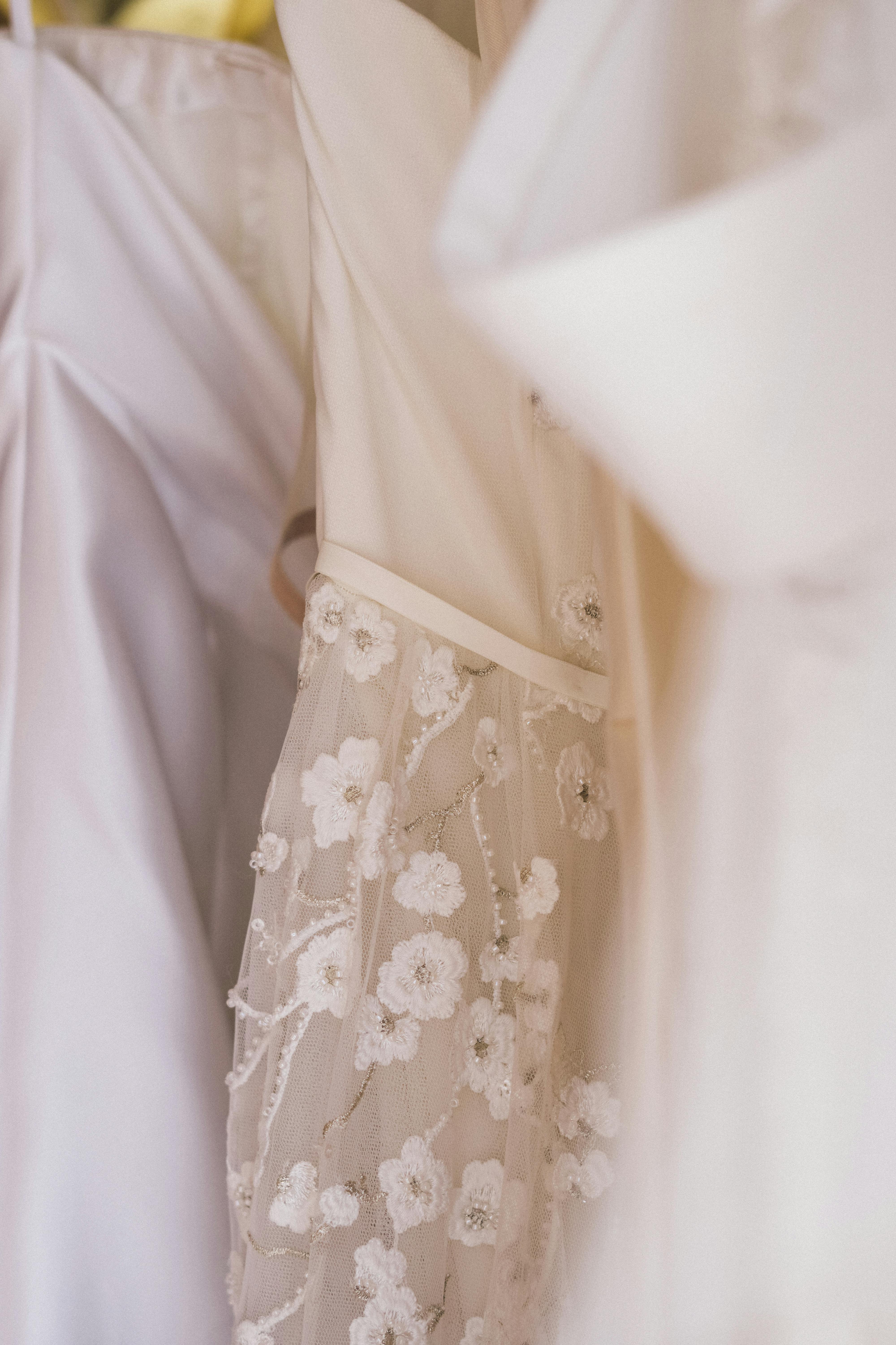Detailed view of a beautiful floral-patterned wedding dress hanging indoors.