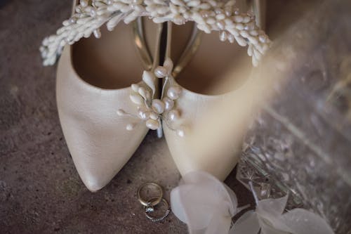 Close-up of Bridal Shoes and Wedding Rings Lying on the Floor 