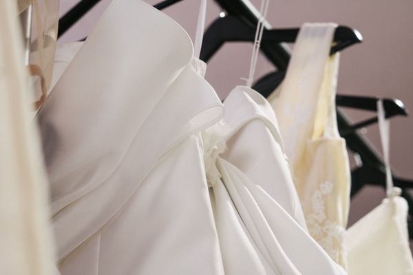 Finished gowns hanging under covers in the fitting room