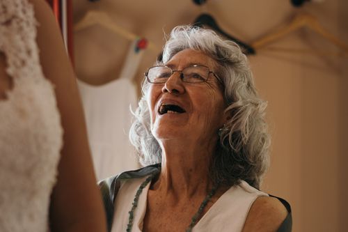 Free An elderly woman wearing glasses and a beaded necklace, joyfully smiling indoors. Stock Photo
