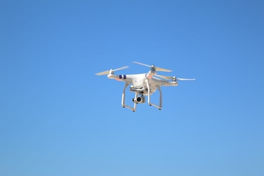 A white drone captured mid-flight against a clear blue sky, showing technology in motion.