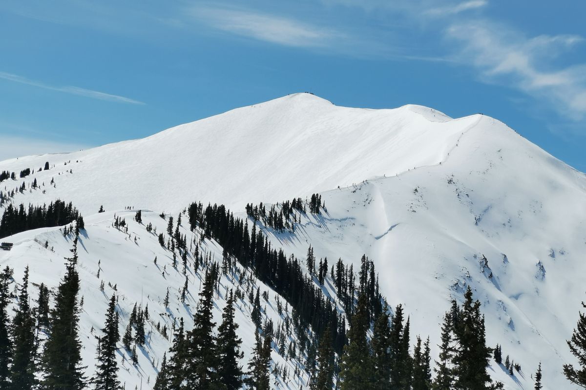 A skier hiking the high snow ridge of Highlands Bowl