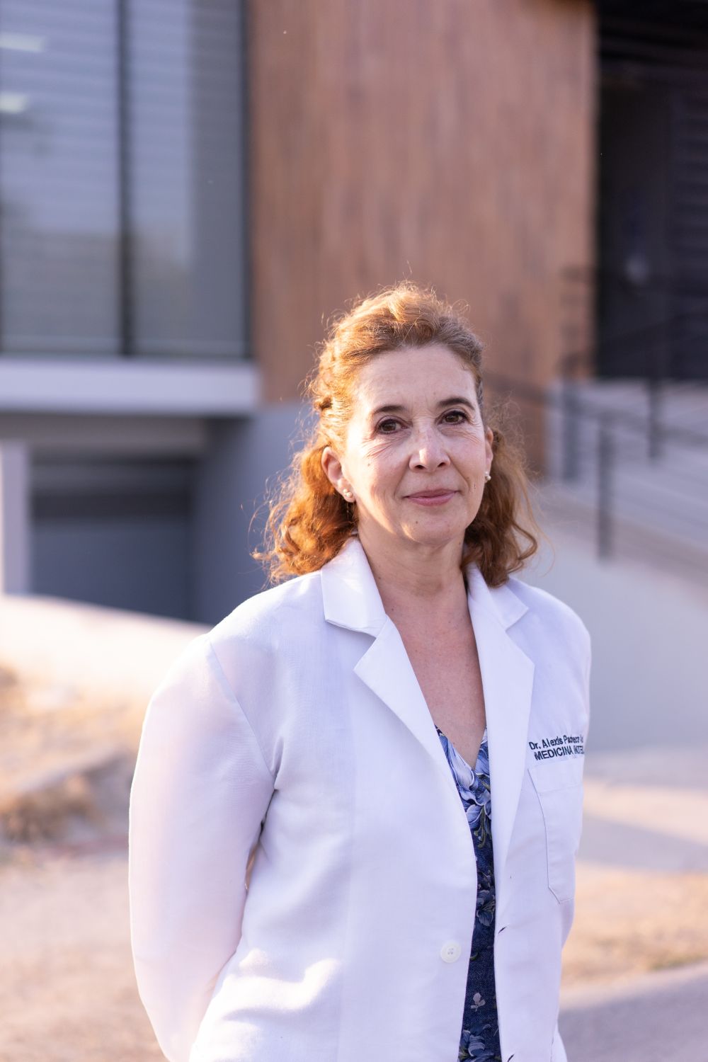 Doctor in a white coat outside a modern medical facility