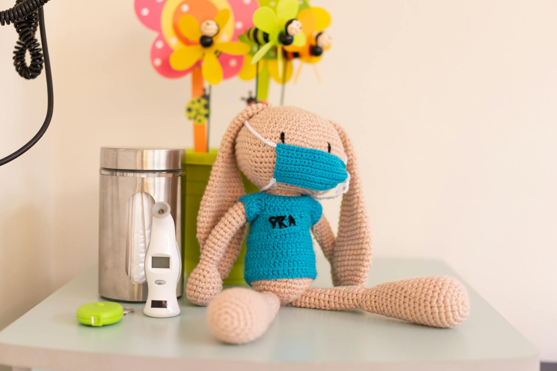 Stuffed Toy with a Face Mask Sitting on Top of a Piece of Furniture Pediatricians Office