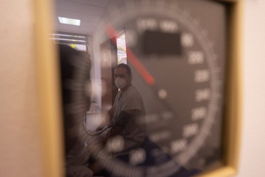 A patient is reflected in a sphygmomanometer during a medical appointment, highlighting the focus on healthcare.