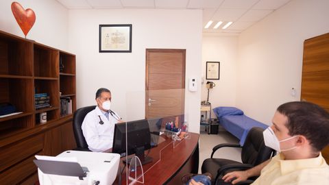 Doctor and patient with masks in medical clinic, emphasizing healthcare safety.