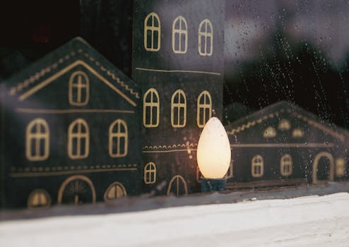 Charming Christmas window display with illuminated wooden decorations and raindrops.