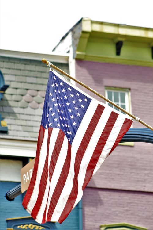 Free An American flag waving in front of a vibrant building facade, showcasing patriotism. Stock Photo
