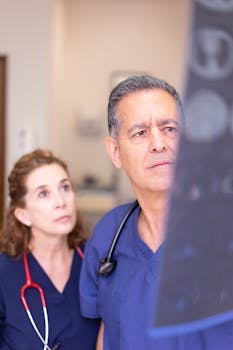 Doctors in blue scrubs reviewing an X-ray image in a hospital environment.