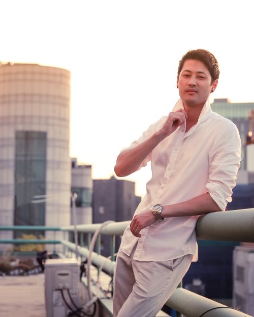 Free Stylish portrait of an East Asian man on a Seoul rooftop during sunset, capturing urban charm. Stock Photo